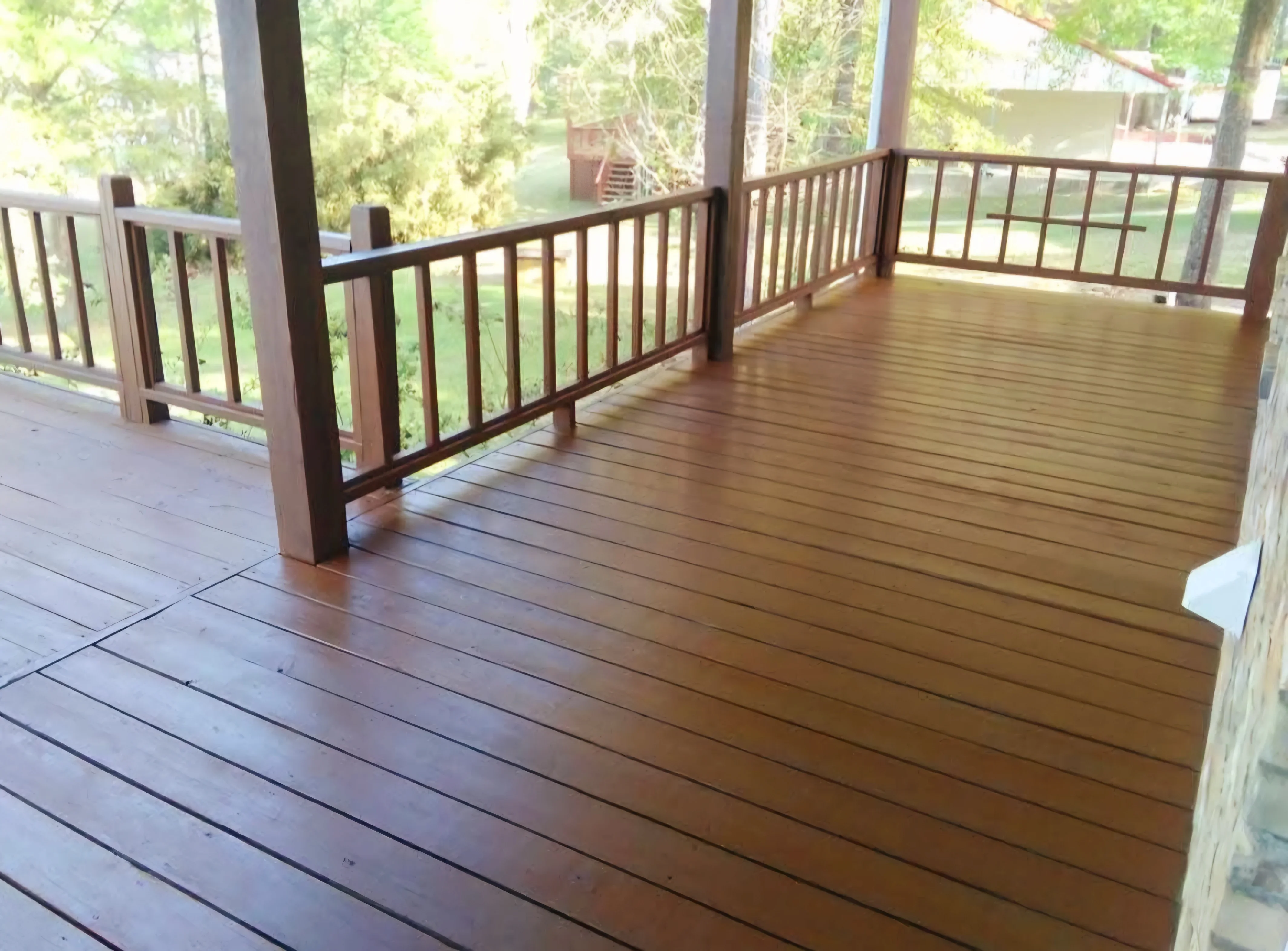 Brown stained deck with wood railing system and vertical balusters overlooking trees