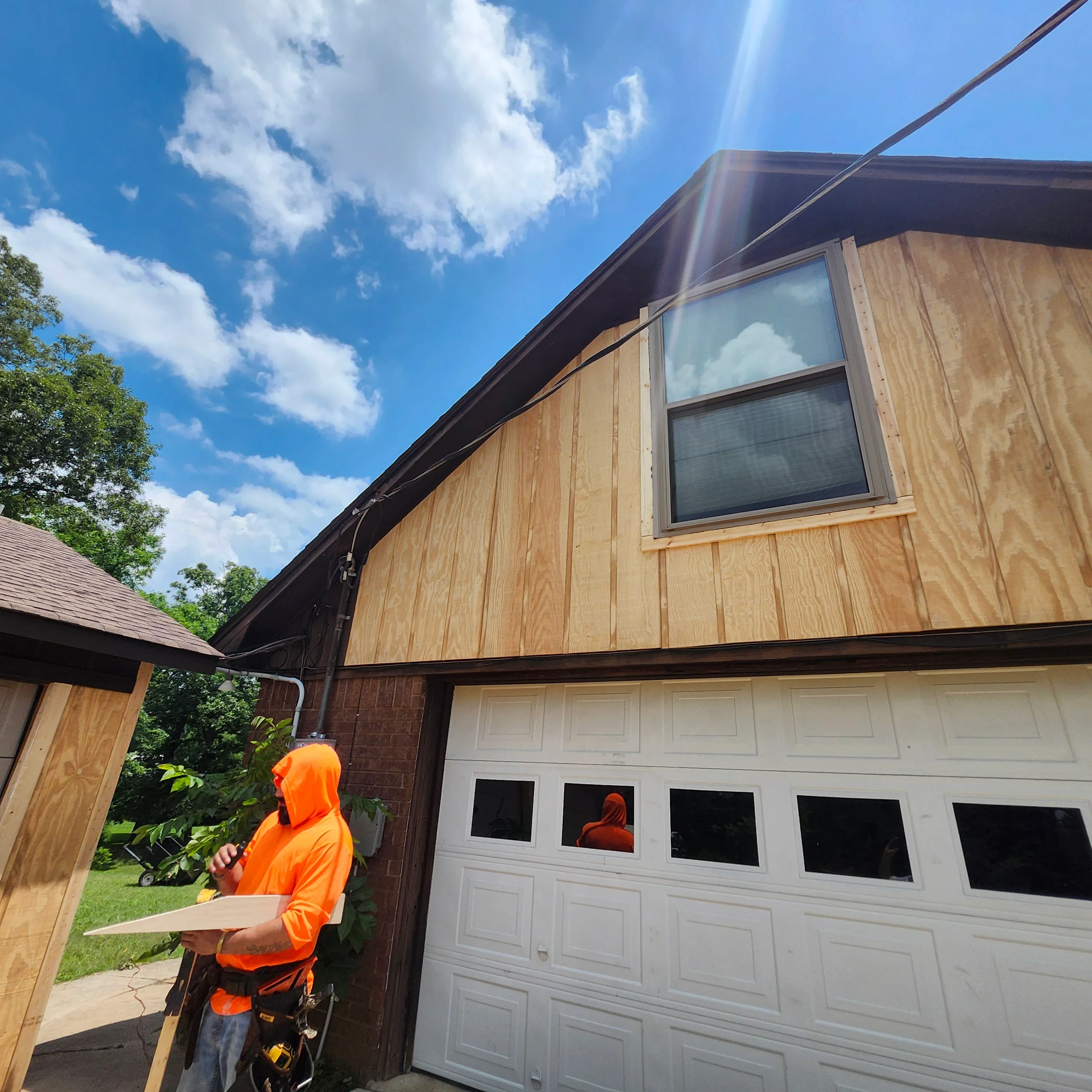 Plywood siding installation with white garage door and dark trim on residential home