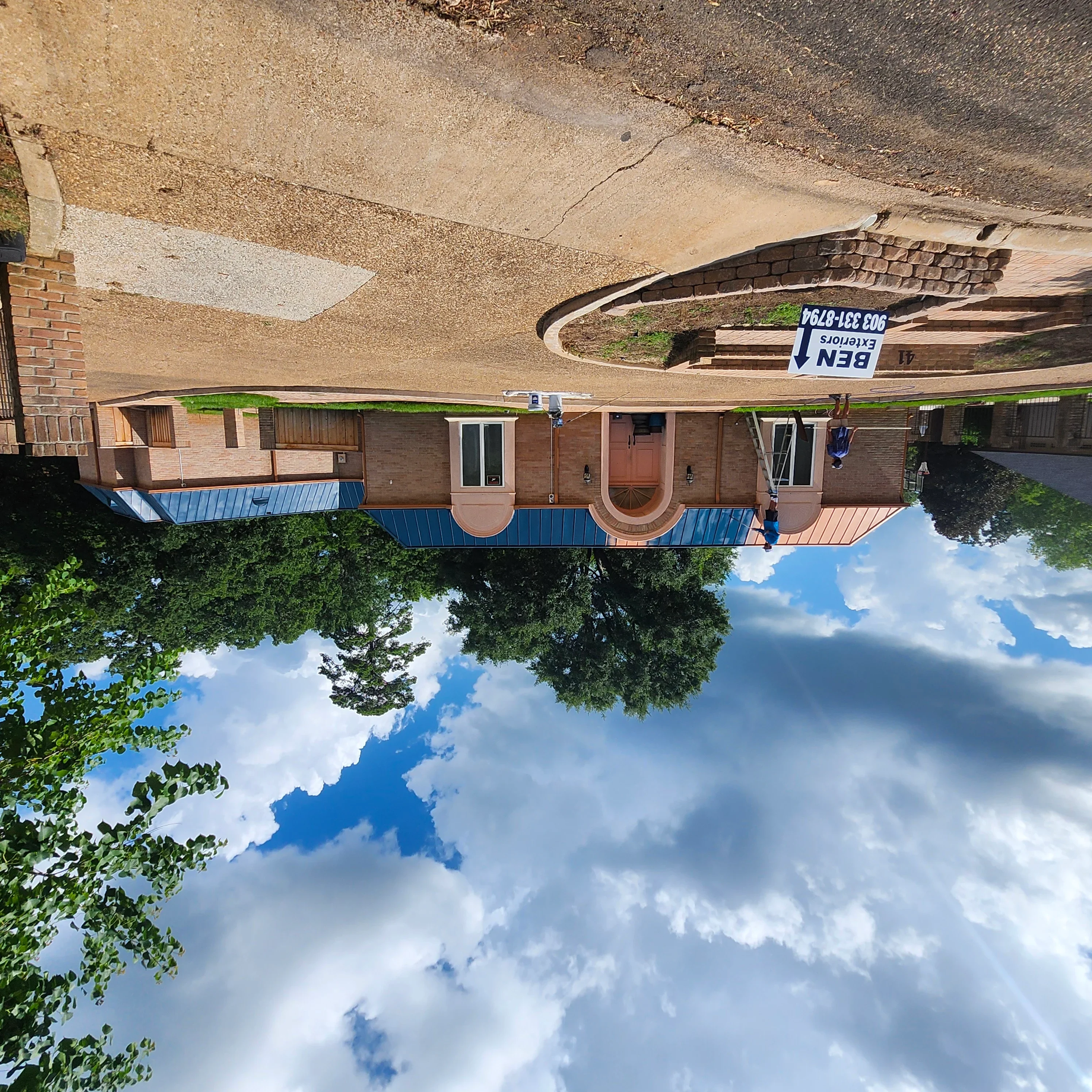 Brick home with blue and copper standing seam metal roof, painted trim, and updated driveway