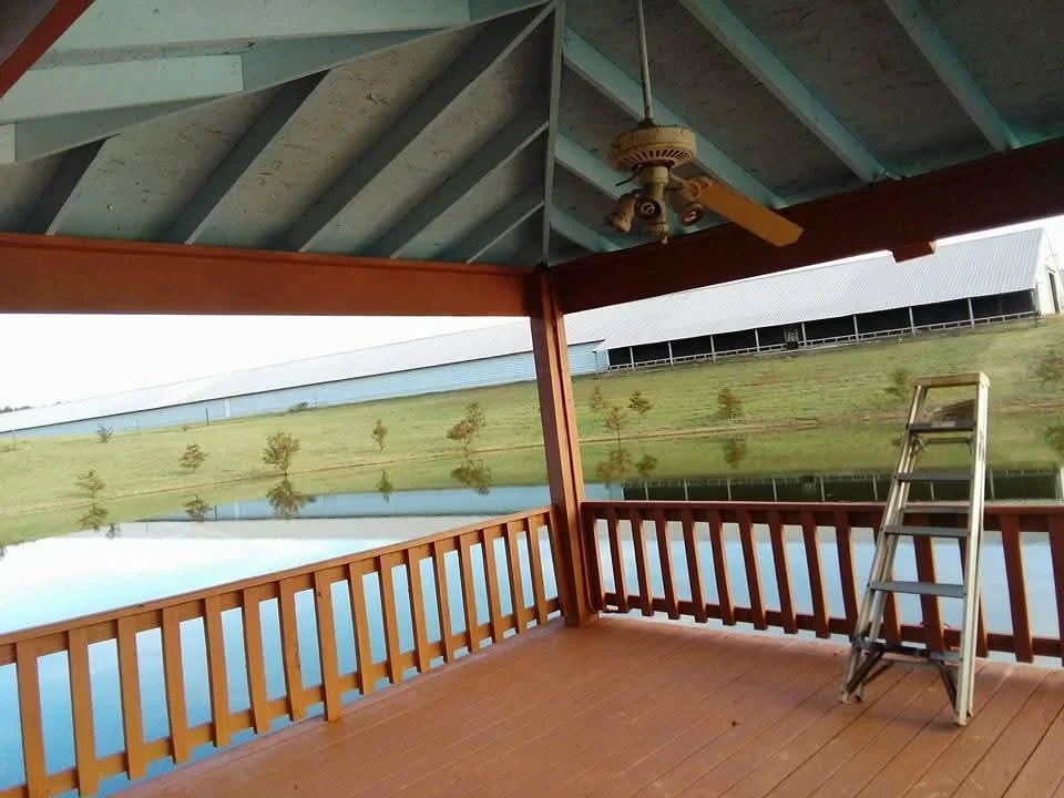 Covered patio with painted blue ceiling, red beams, and wooden railings