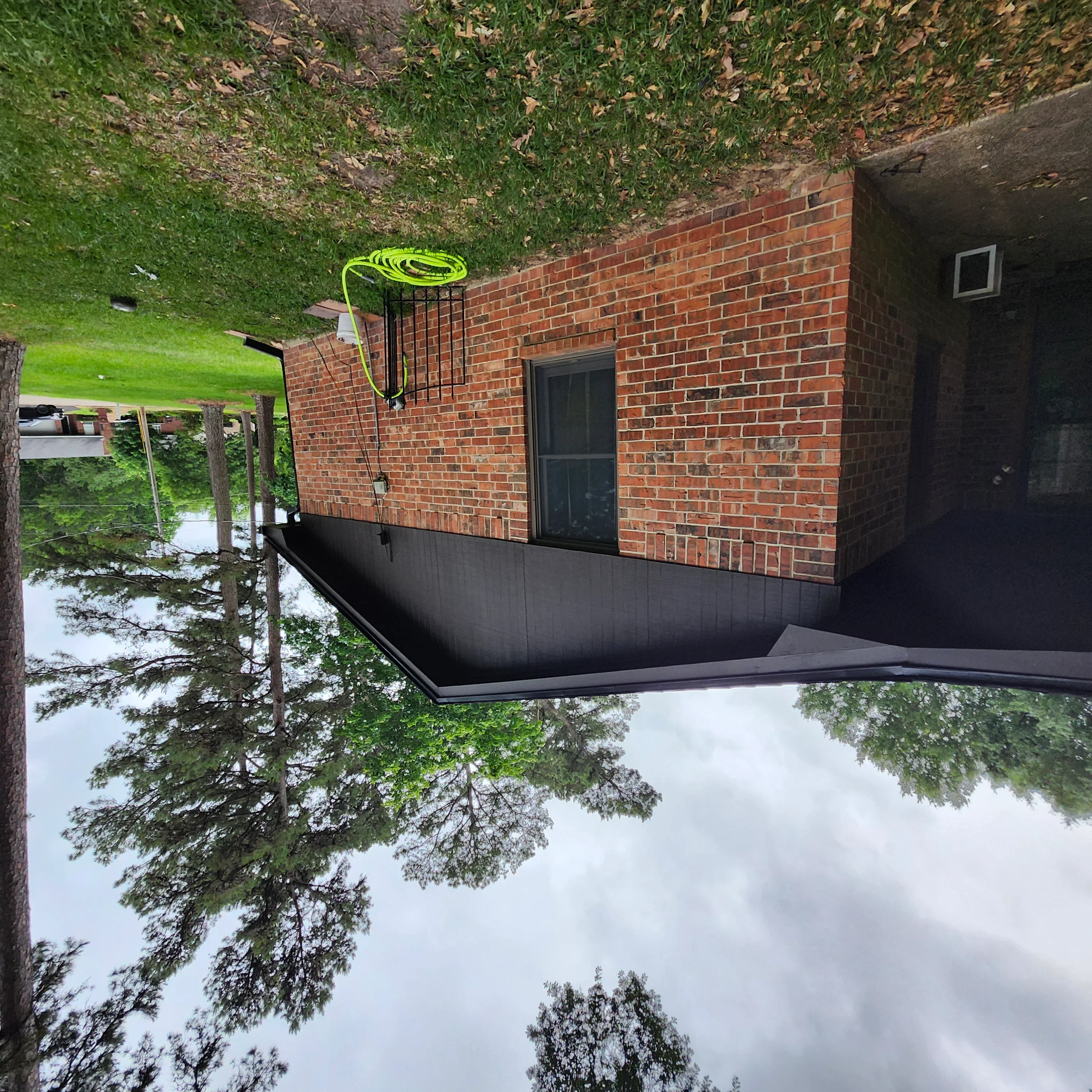 Black waterproof coating applied to brick foundation wall of residential building