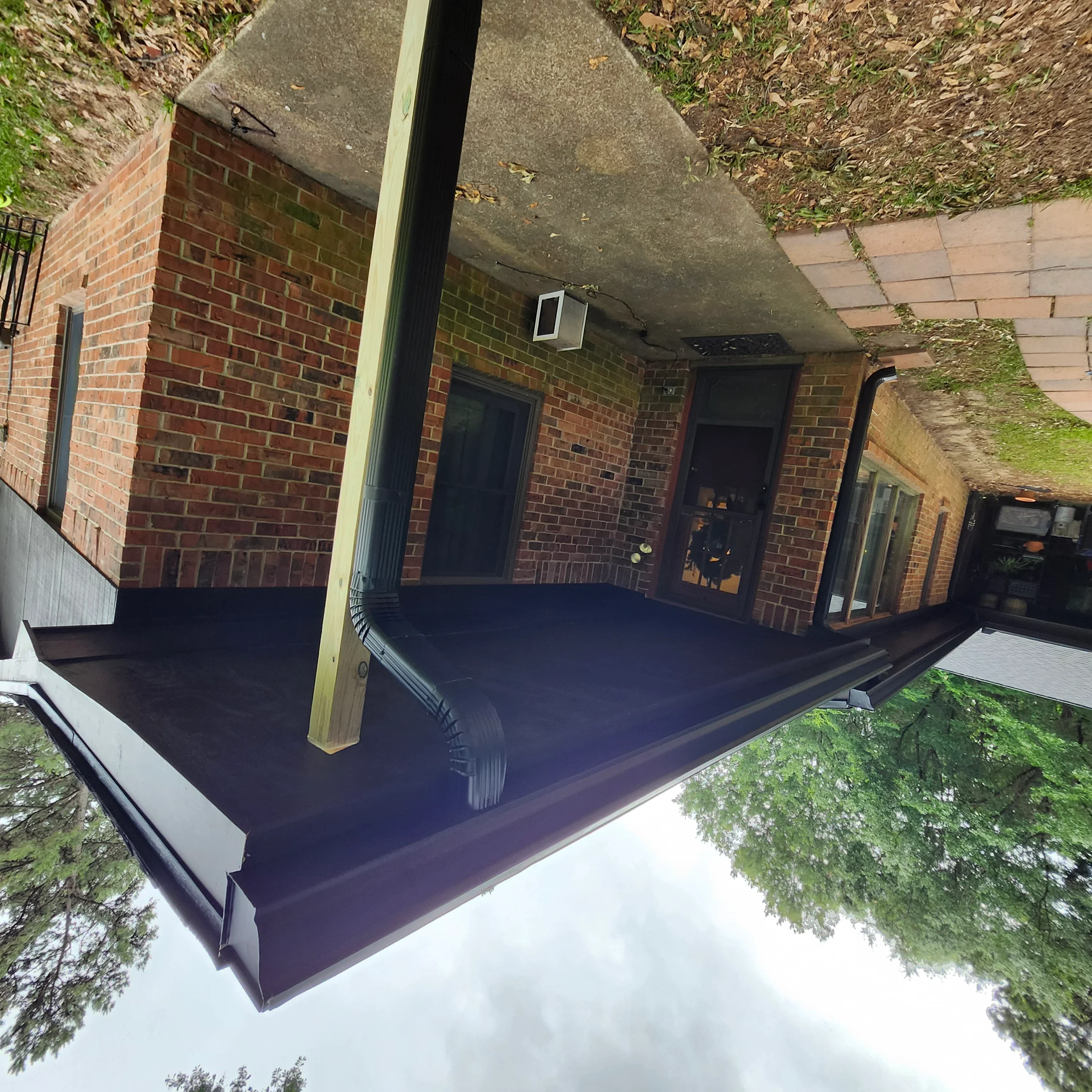 Dark navy protective coating applied to concrete underpass soffit above brick structure