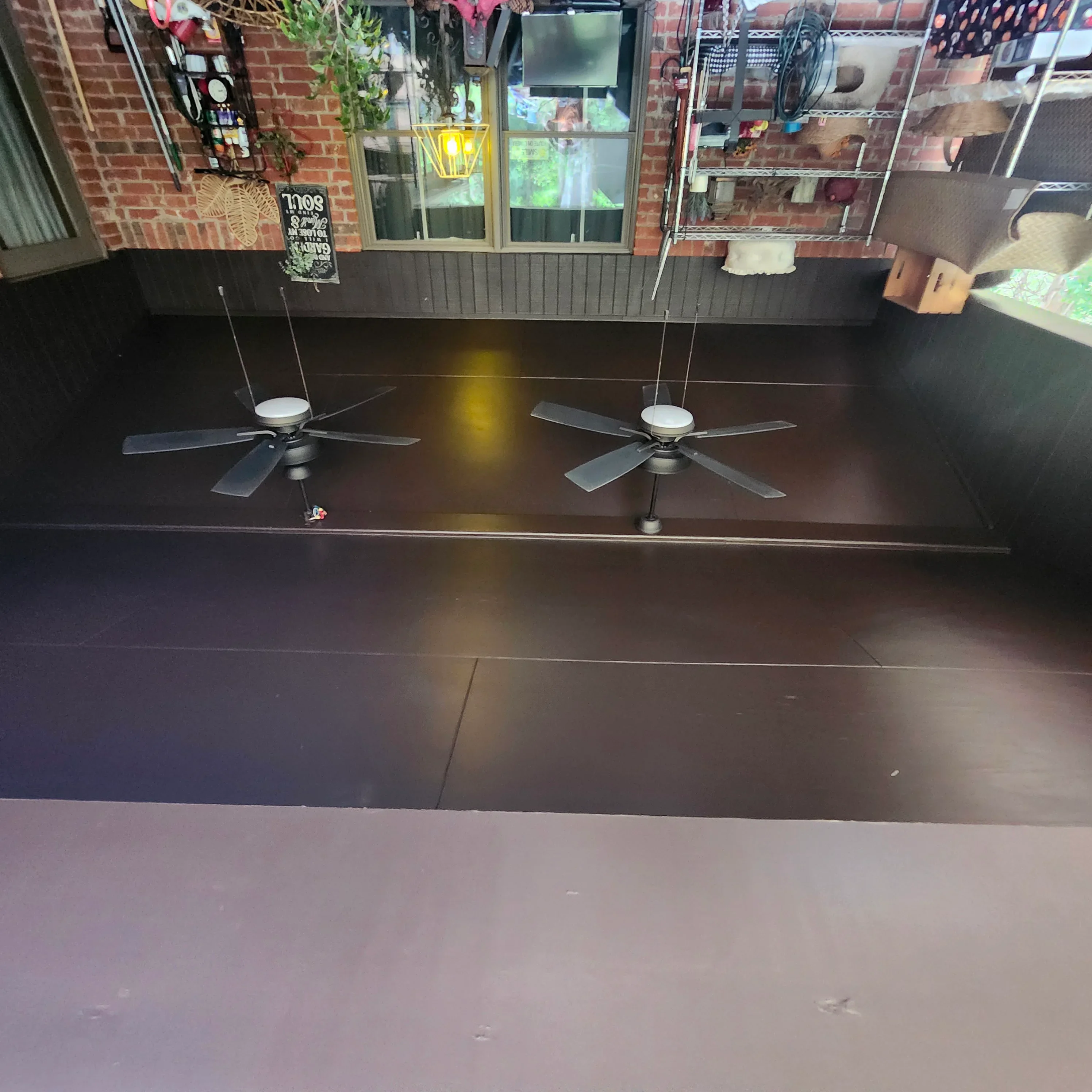 Dark epoxy floor coating with ceiling fans in commercial space with brick walls