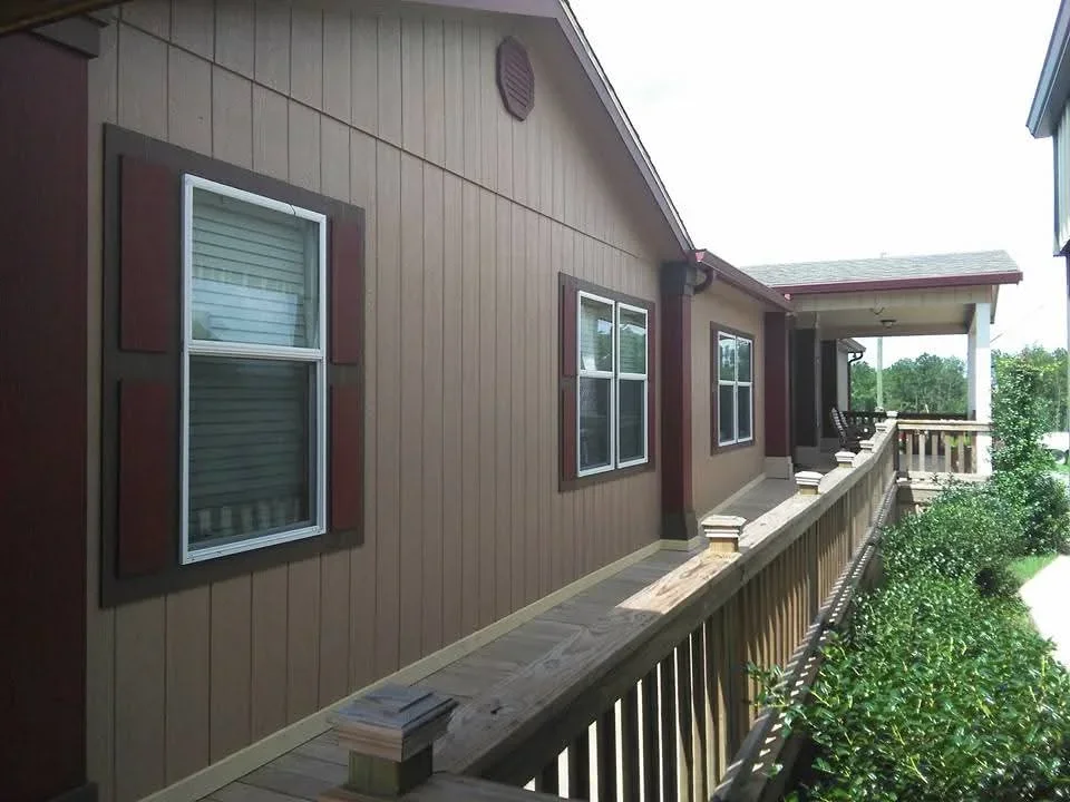 Metal siding painted taupe with burgundy window trim and shutters on residential exterior