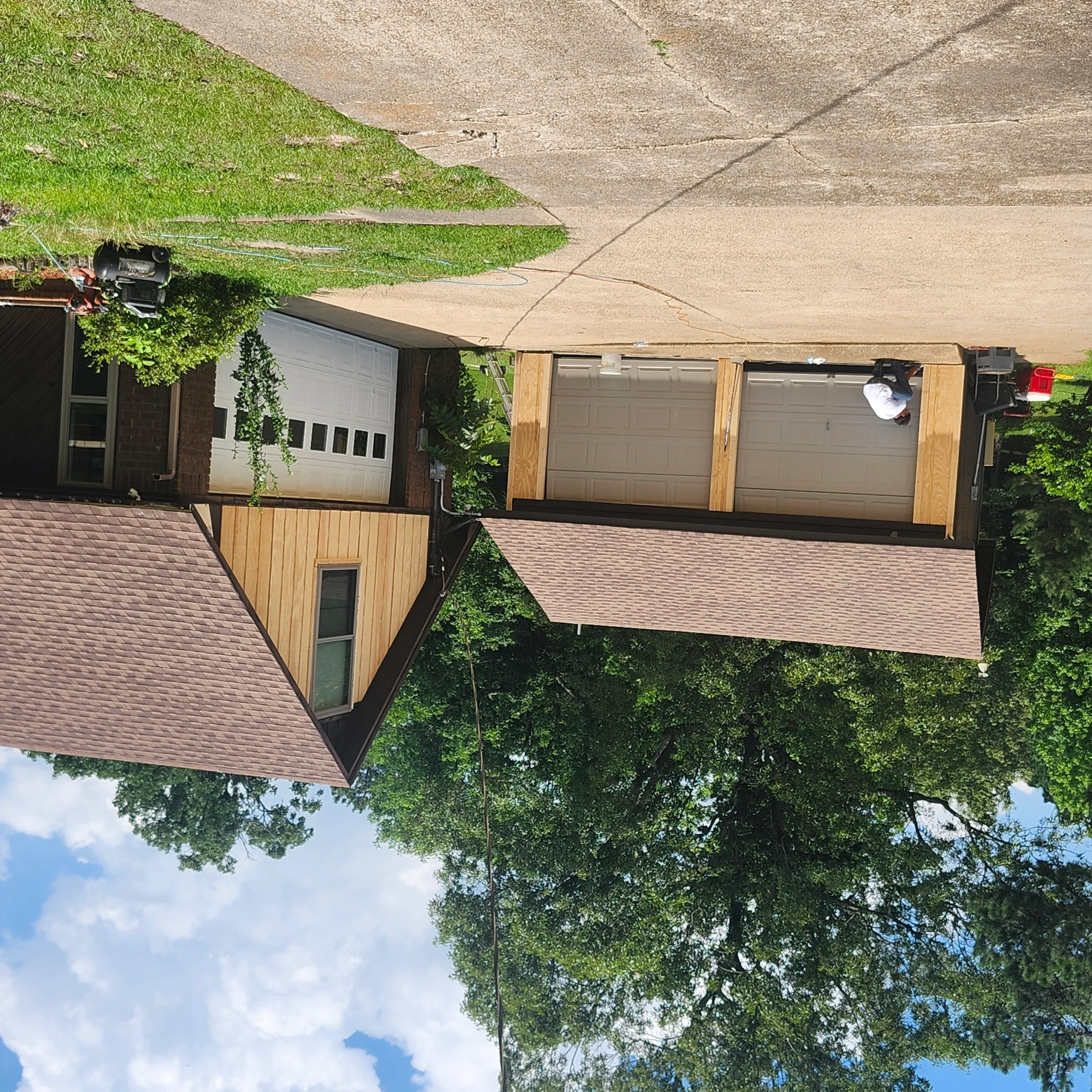Three garage doors with newly painted frames and natural wood trim installation on residential home