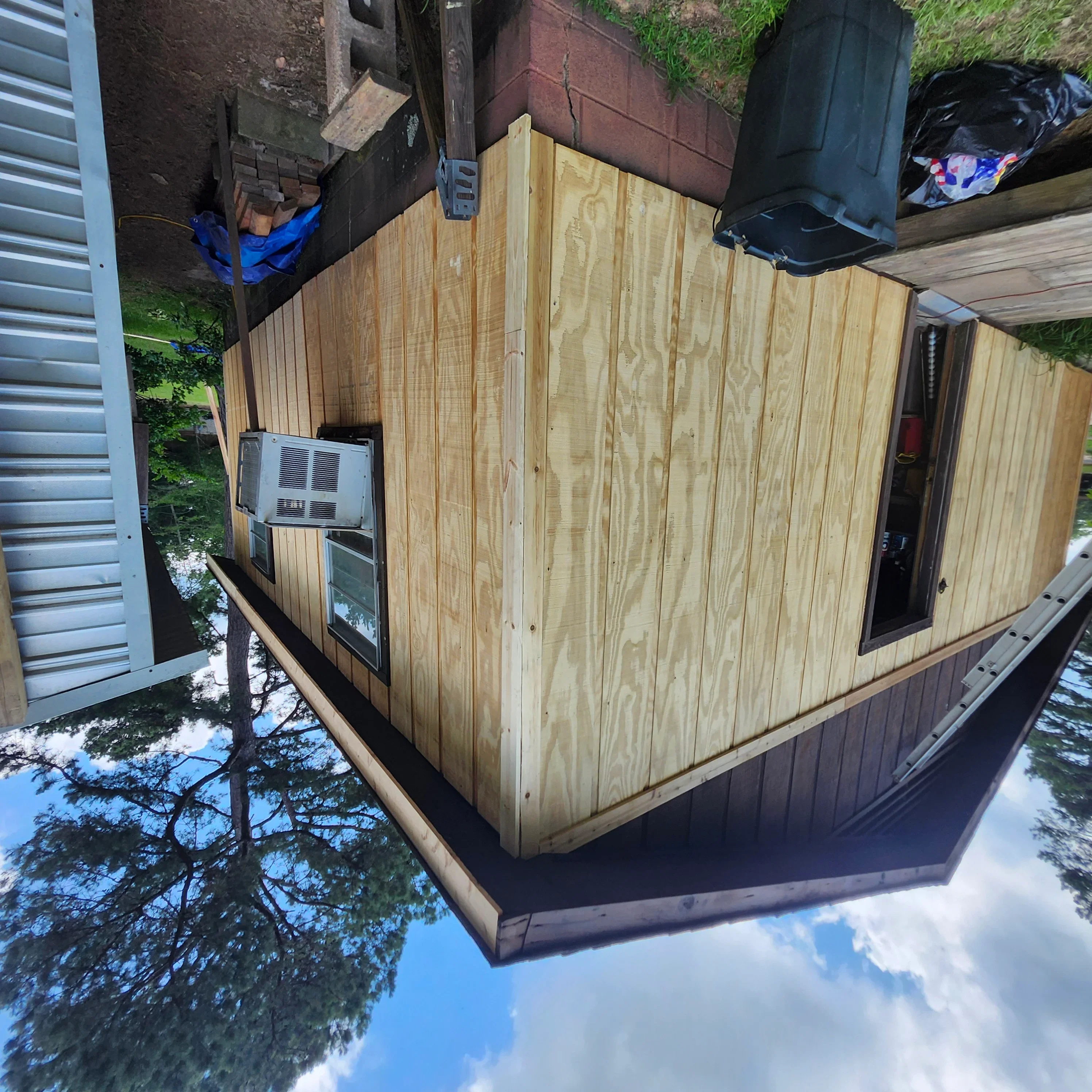 Vertical wood siding installation with window opening and natural stain finish on exterior structure