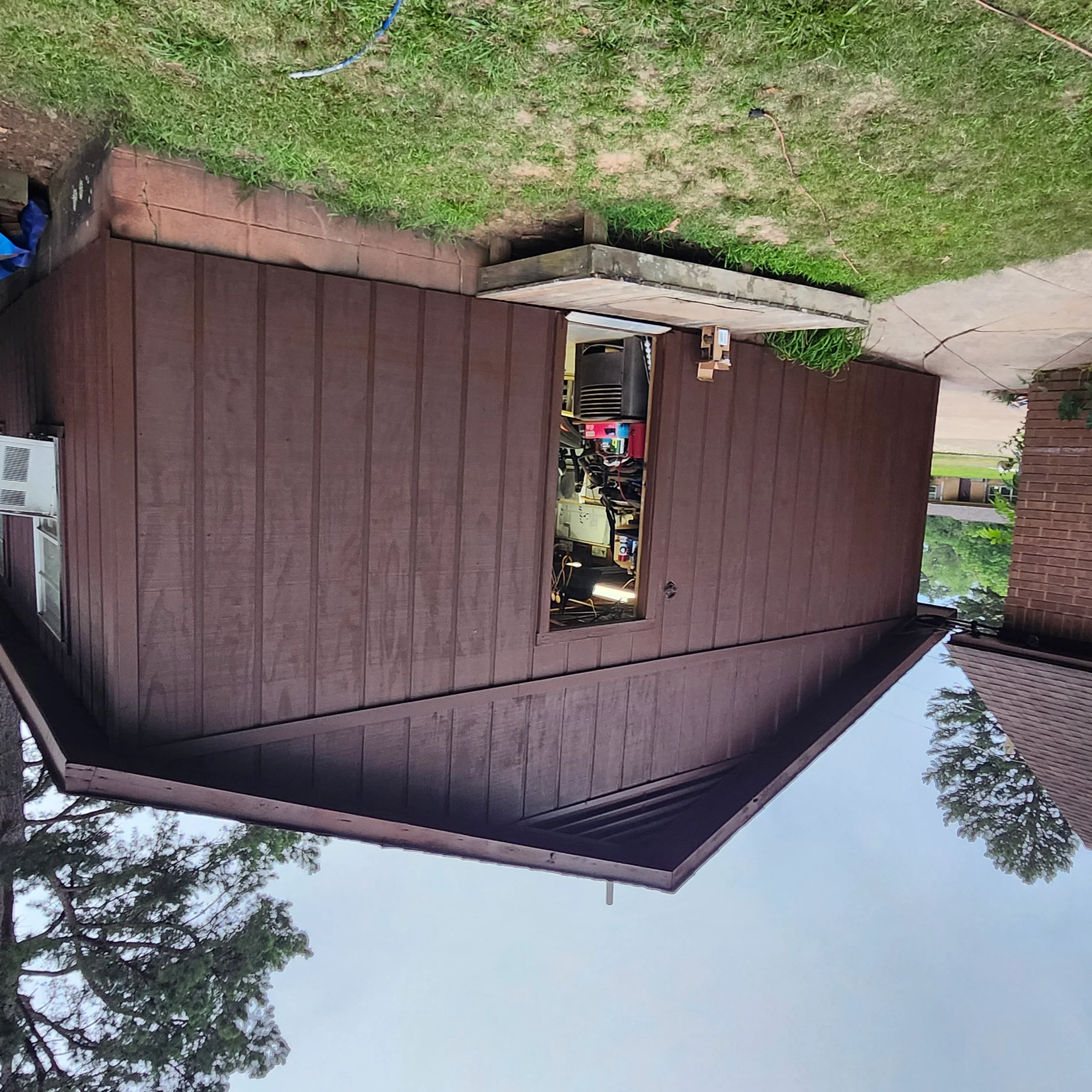 Dark brown painted metal utility shed with vertical panel siding and sloped roof