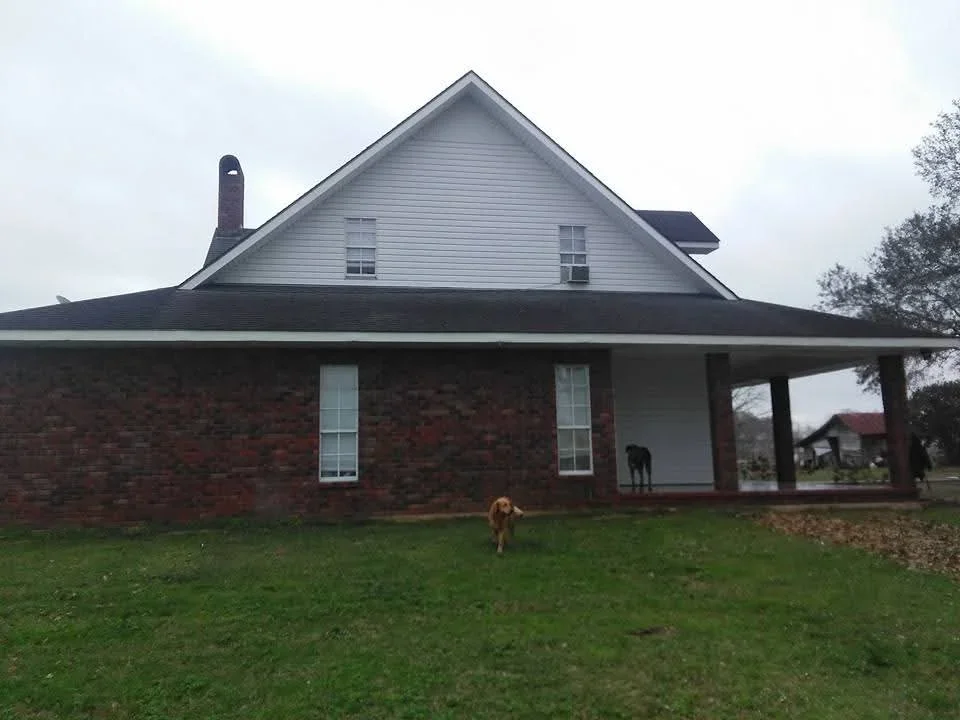 Brick home with newly painted white upper gable and fresh siding on front porch structure