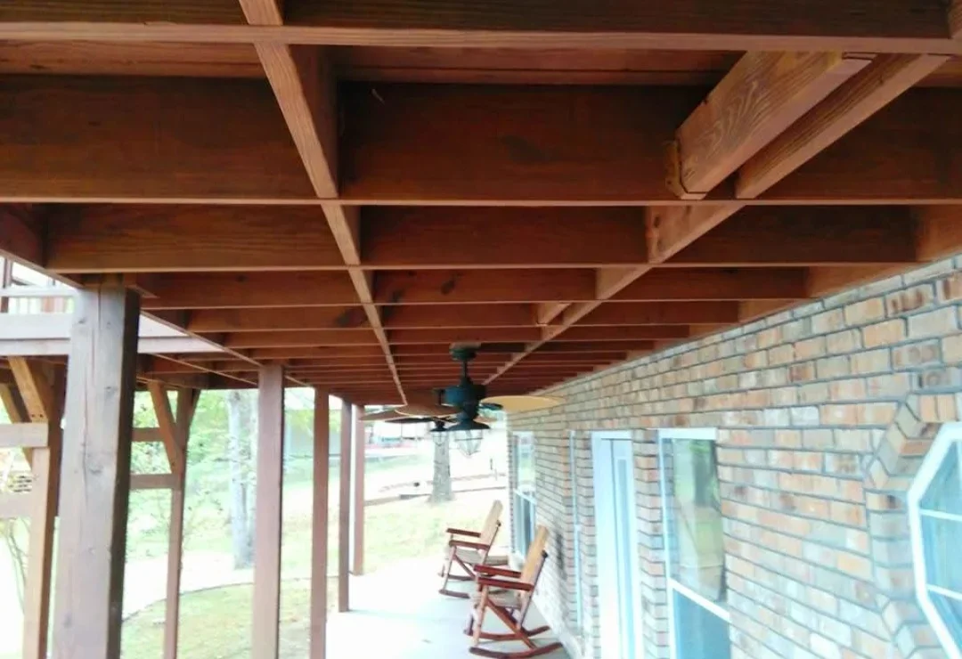 Exposed wood beam ceiling with medium-brown stain finish on covered porch structure