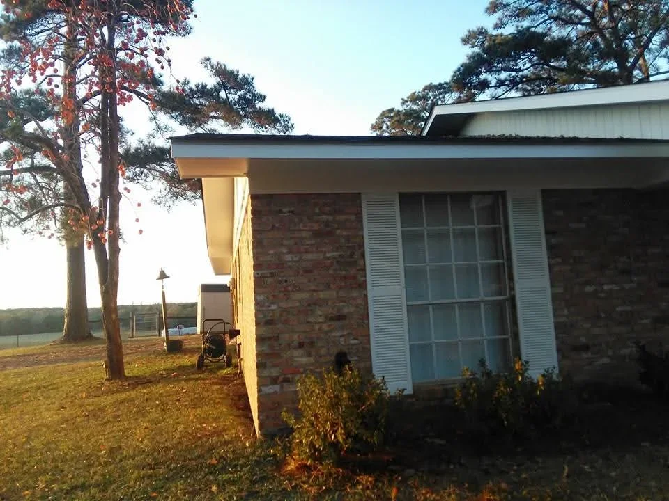 Brick home exterior with freshly painted white trim, shutters, and fascia against natural brick walls