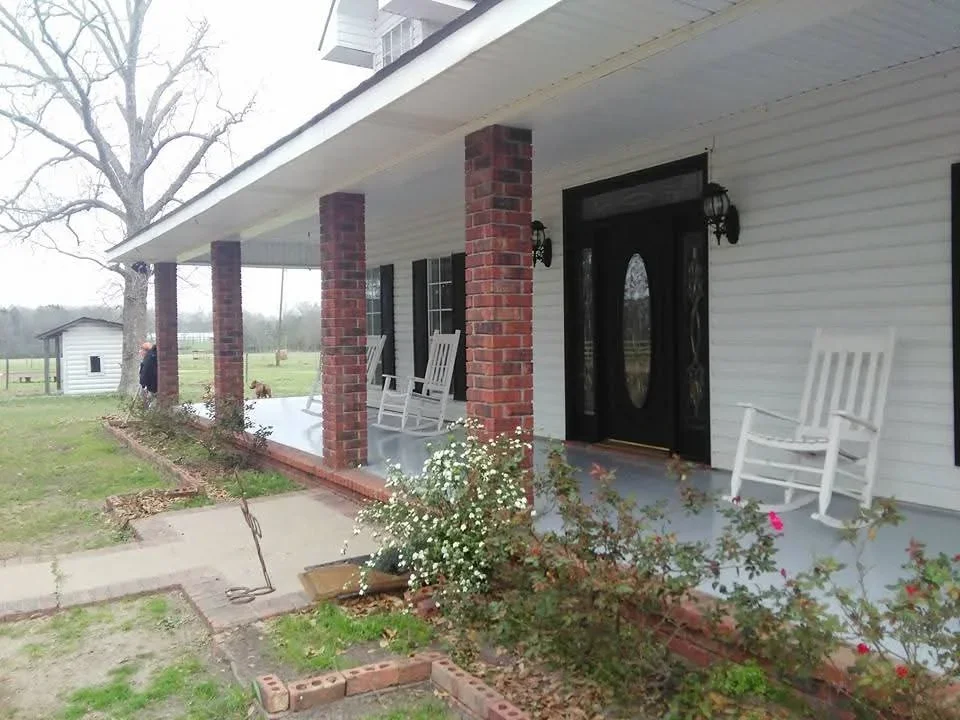 White painted siding with black entry door and brick porch columns on residential home