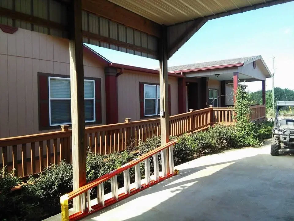 Burgundy metal siding with painted wood railings and trim on mobile home exterior