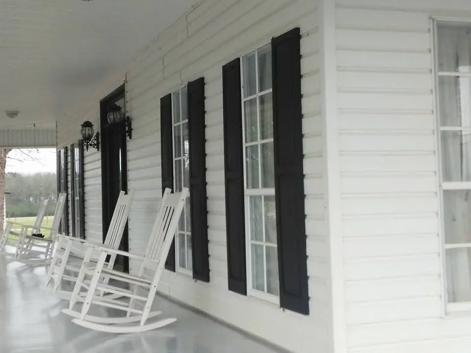 White painted house exterior with black shutters and white trim windows