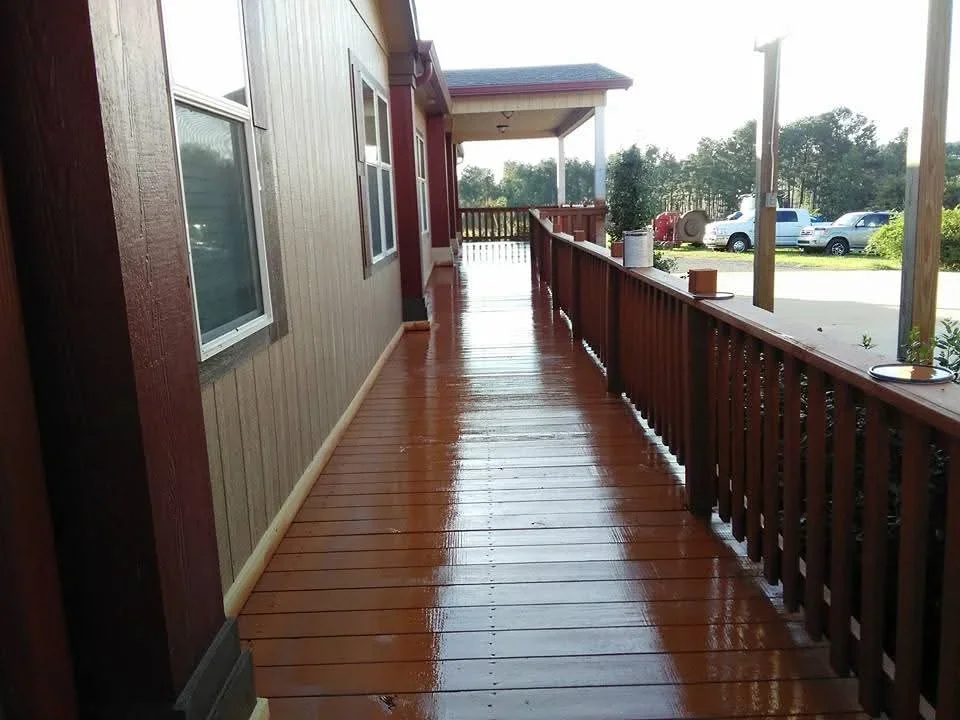 Freshly stained brown wooden deck with railings and covered porch extension